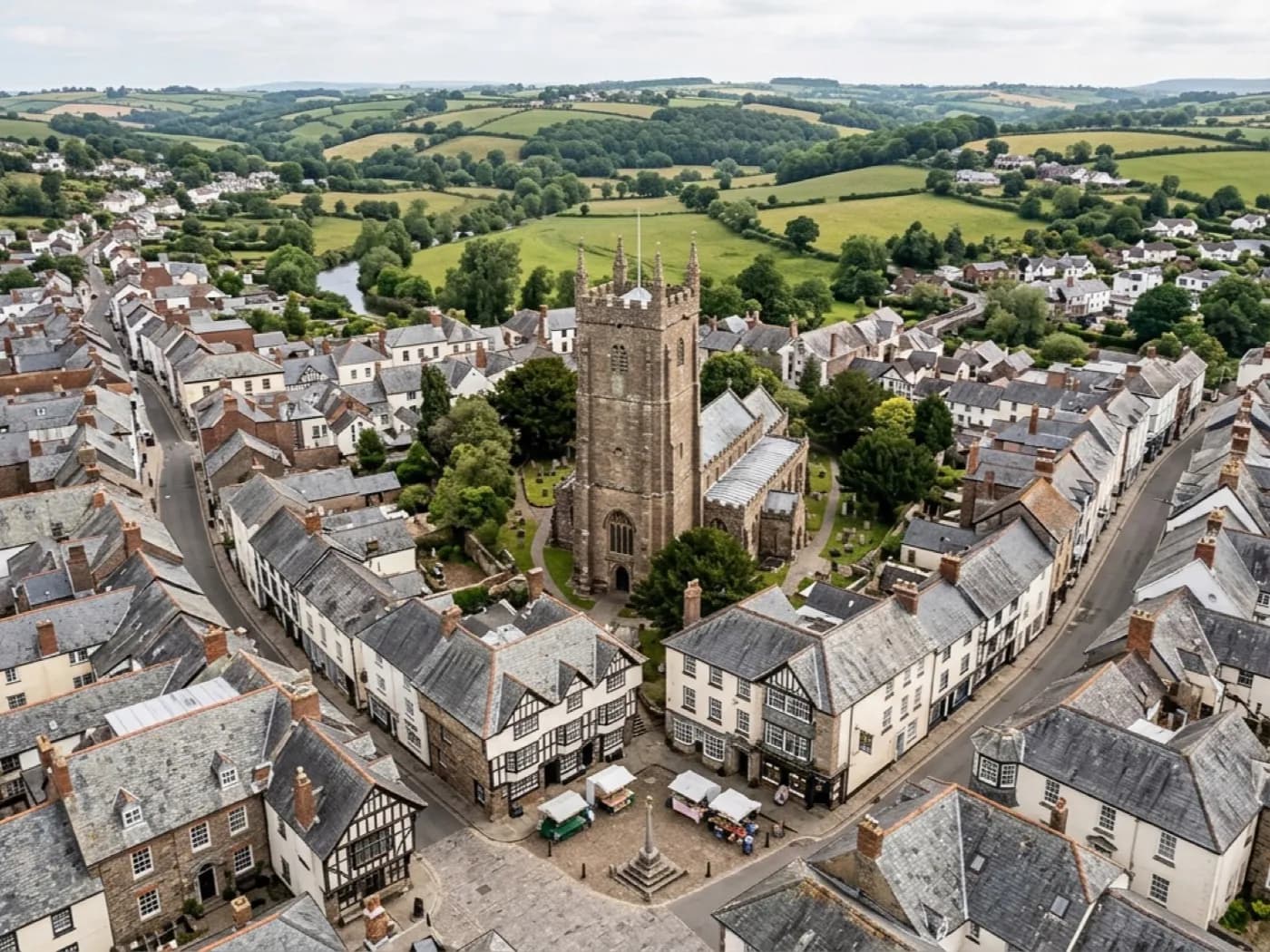 Aerial view of a historic market town centre, a church tower and a grid of old streets and rooftops